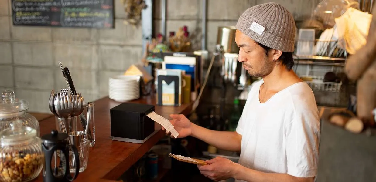 Cafe worker tearing off a printed ticket at the counter