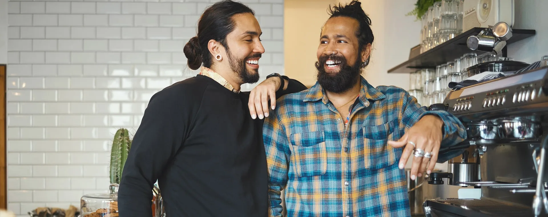 Two cafe owners standing together behind their espresso bar
