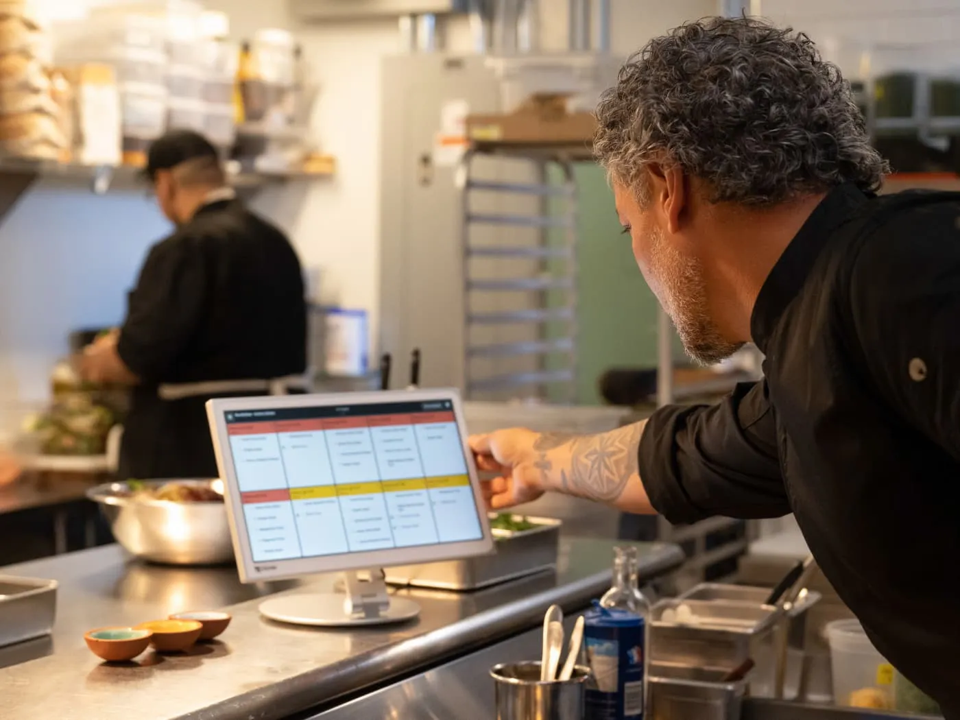 Chef checking orders on a Clover kitchen display in a busy kitchen